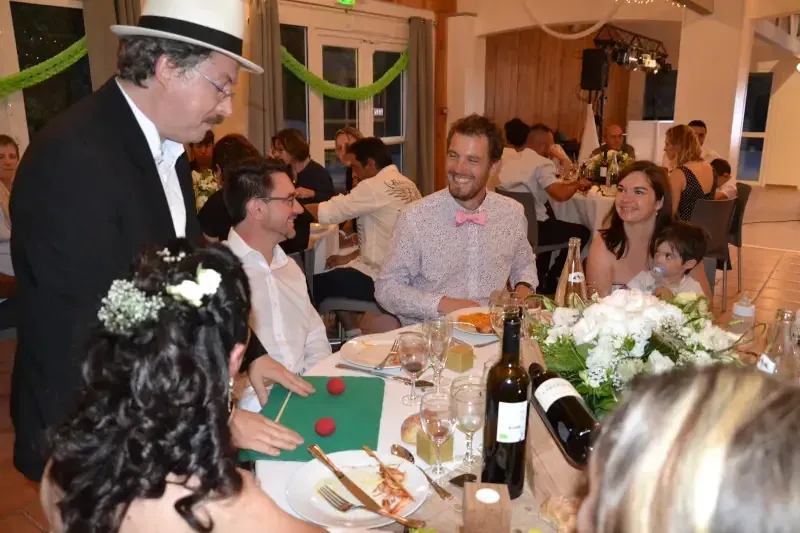 Sylvio le magicien fait un tour de cartes à une table de mariage, la mariée au premier plan